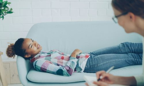 Girl lying on couch during therapy session with counselor